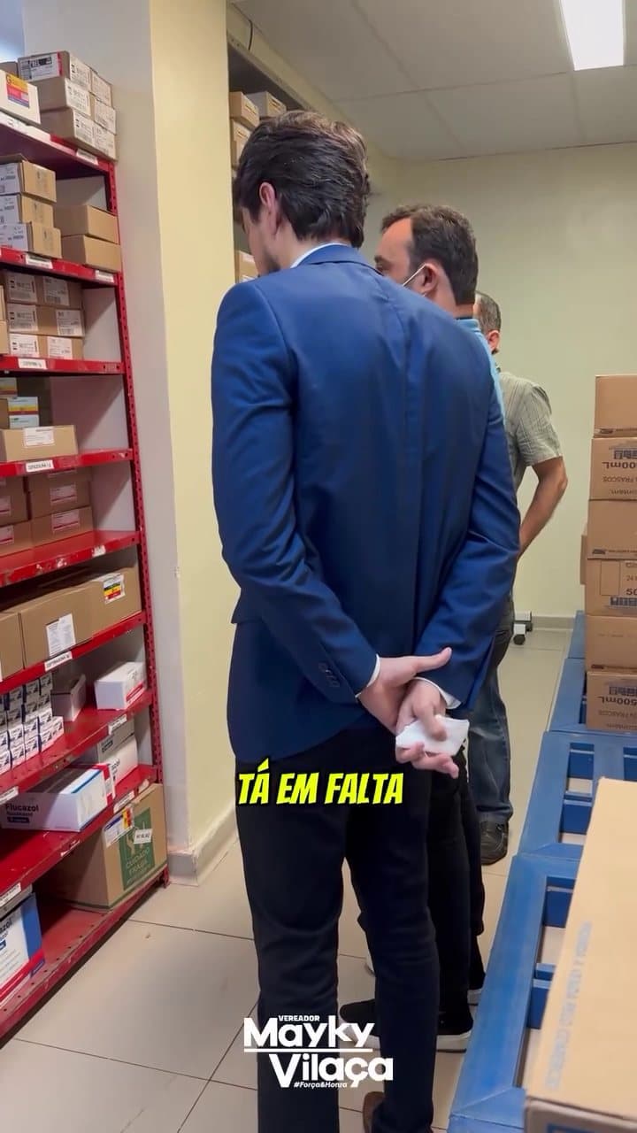Mayky Vilaça fiscalizando o estoque de medicamentos, segurando uma caixa.